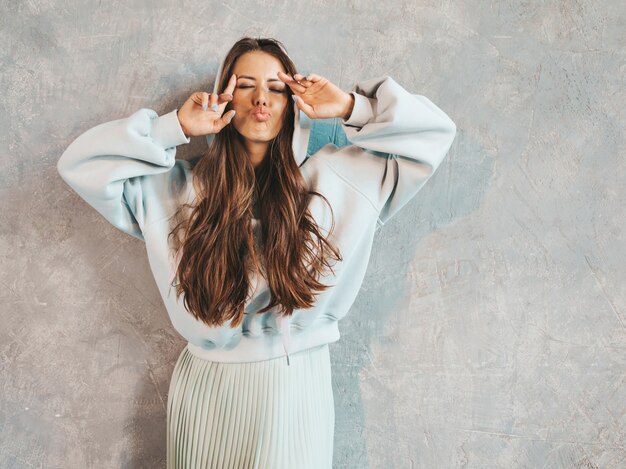 Junges schönes lächelndes Frauenschauen. Modisches Mädchen in der zufälligen Sommer Hoodie- und -rockkleidung. . Zeigt ihre Zunge