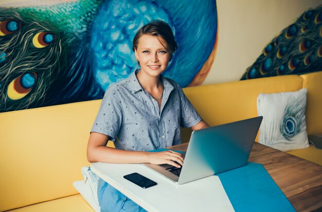 junges schönes Mädchen benutzt einen Laptop im Café und surft das Internet