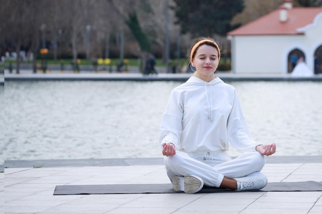 Junges schönes Mädchen, das Meditation auf Yogamatte im Park macht Foto in hoher Qualität