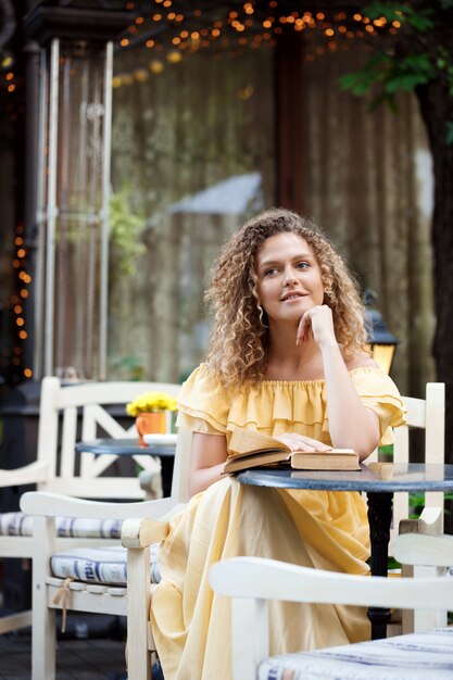 Junges schönes Mädchen liest, sitzt im Café.