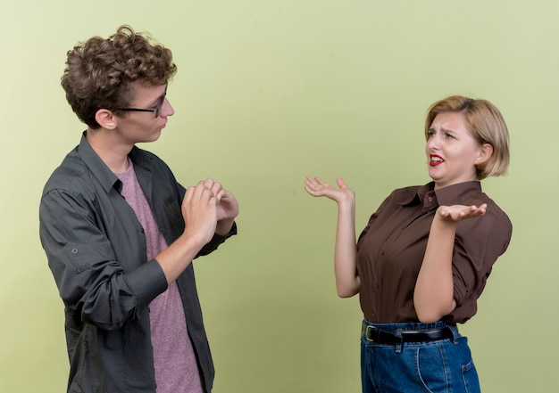 Kostenloses Foto junges schönes paar, das lässige kleidung trägt, die einander streit, der über heller wand steht