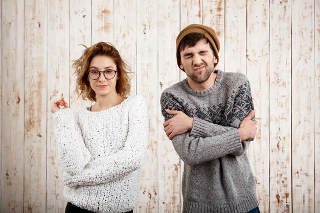 Junges schönes Paar, das über Holzwand aufwirft