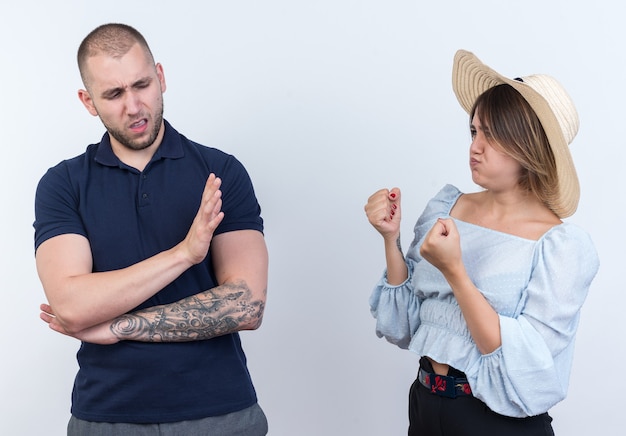 Junges schönes Paar Mann und Frau streiten wütende Frau mit geballten Fäusten, die ihren Freund anschaut, der mit der Hand eine Stopp-Geste macht