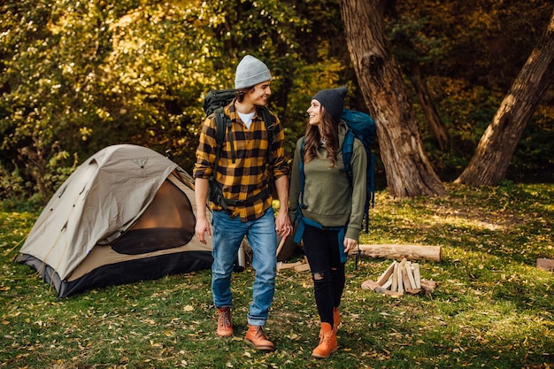 Junges schönes Paar mit Wanderrucksäcken geht campen