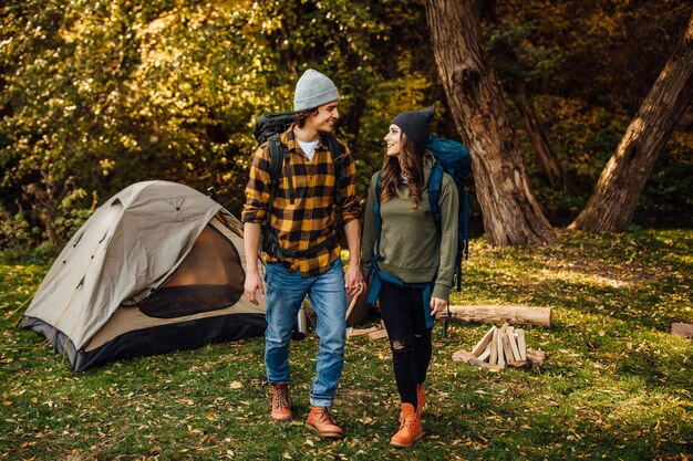 Junges schönes Paar mit Wanderrucksäcken geht campen