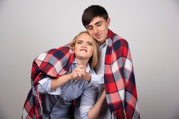 Junges schönes Paar steht in einer karierten Decke und posiert