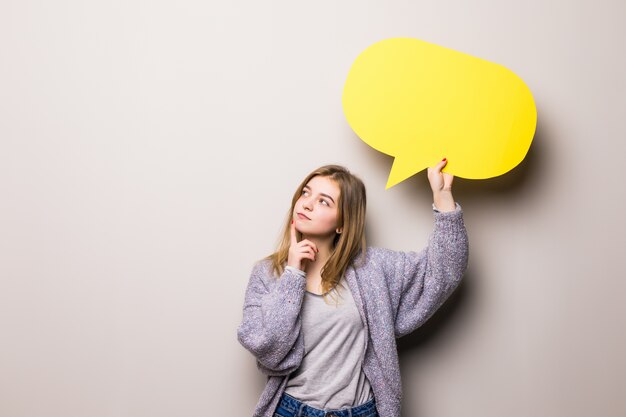 Junges schönes träumendes Mädchen, das eine gelbe Blase für Text hält, lokalisiert