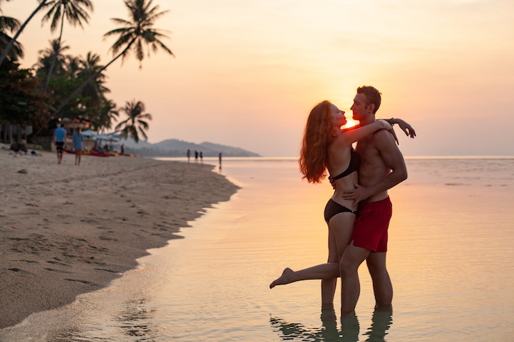 Kostenlose Foto junges sexy romantisches paar verliebt in sonnenuntergang glücklich am sommerstrand zusammen mit spaß, badeanzüge tragend