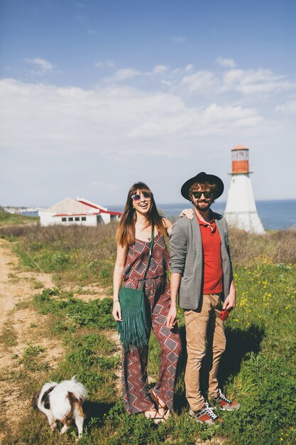 Junges stilvolles Hipster-Paar in der Liebe, die mit Hund in der Landschaft geht