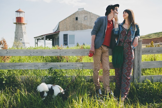 Junges stylisches Hipster-Paar in der Liebe, das mit Hund auf dem Land spazieren geht