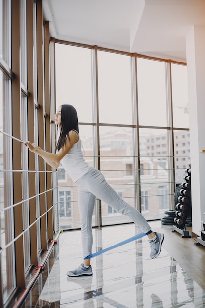 junges und dünnes Mädchen in einem weißen Hemd und graue Gamaschen engagierten sich im Sport im Fitnessstudio