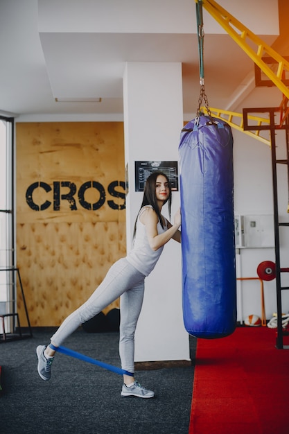 junges und dünnes Mädchen in einem weißen Hemd und graue Gamaschen engagierten sich im Sport im Fitnessstudio