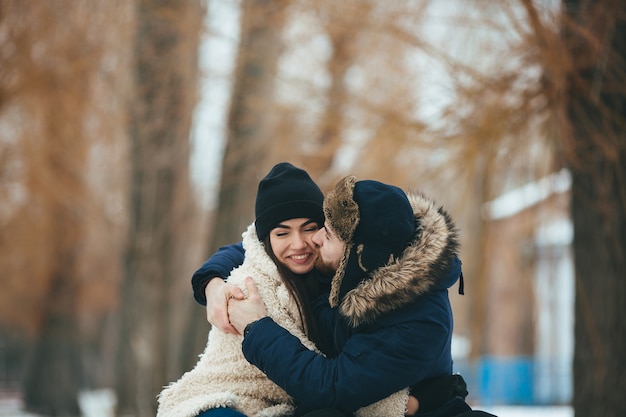 Junges und liebes Paar, das im Winterpark umarmt