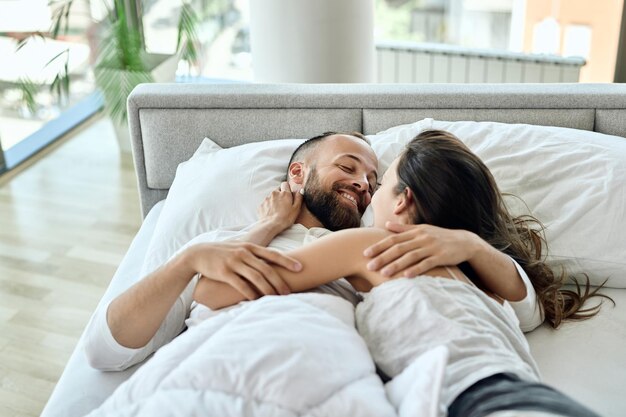 Junges verliebtes Paar, das Zuneigung zeigt, während es im Schlafzimmer kommuniziert
