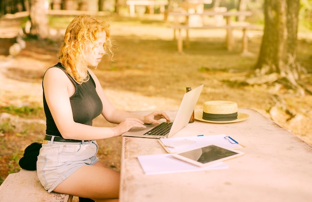 Junges weibliches Graseninternet auf Laptop im Park