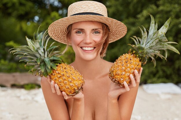 junges weibliches Model posiert mit zwei exotischen Ananas