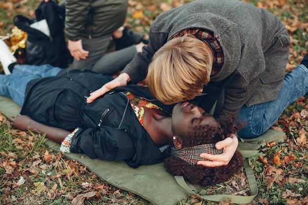 Kostenloses Foto jungs helfen einer frau. afrikanisches mädchen liegt bewusstlos. erste hilfe im park leisten.