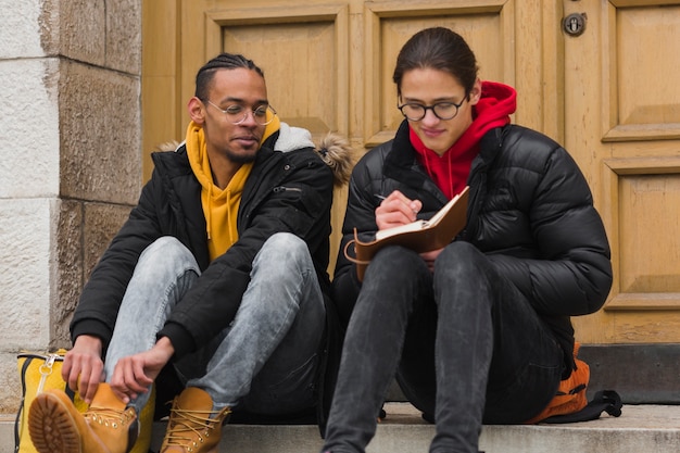 Jungs sitzen auf Treppen mit Notizbuch