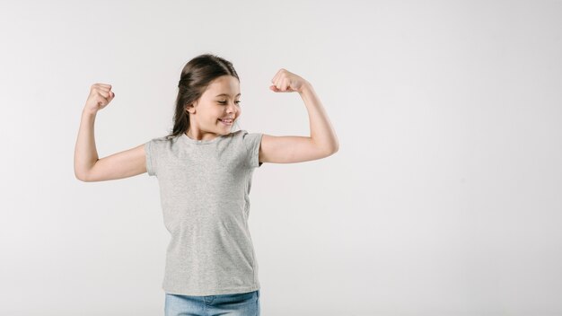 Juniormädchen, das Muskeln im Studio zeigt