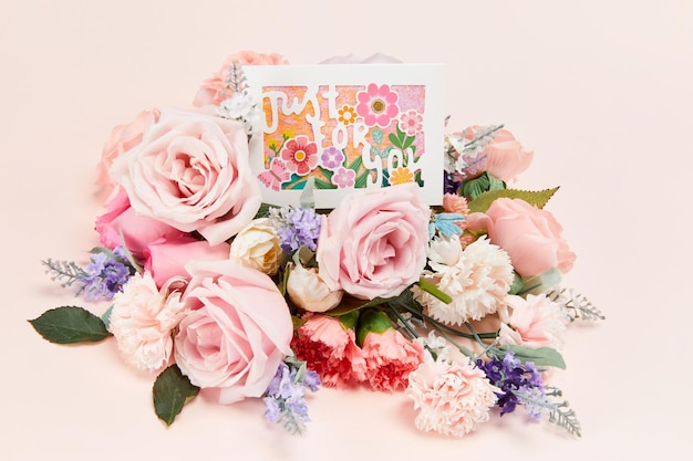 "Just For You"-Botschaft auf Blumen vor einem rosa Hintergrund
