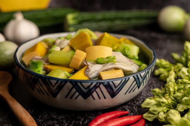 Kaeng Liang in einer Schüssel mit Gewürzen auf einem schwarzen Zementboden.