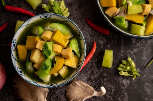 Kaeng liang in einer schüssel mit gewürzen auf einem schwarzen zementboden.