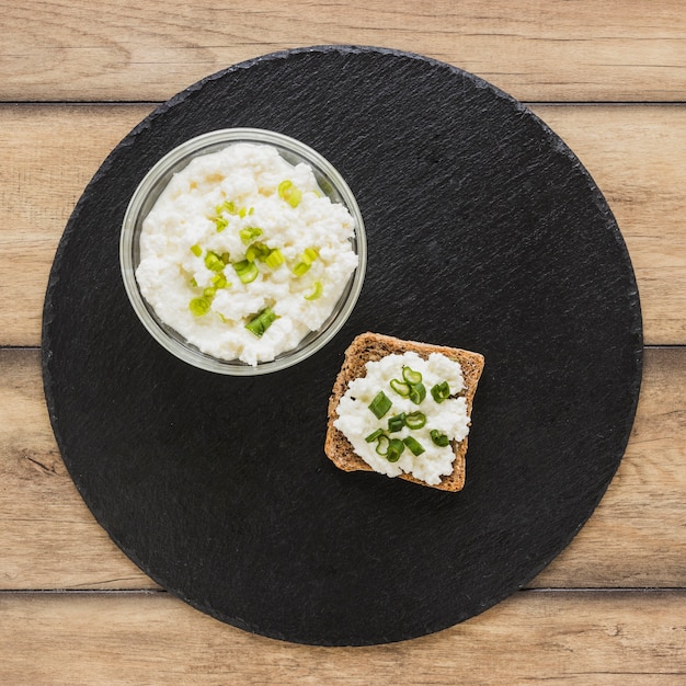 Käse auf Schwarzbrot über dem schwarzen Schieferumhüllungsbrett auf Schreibtisch