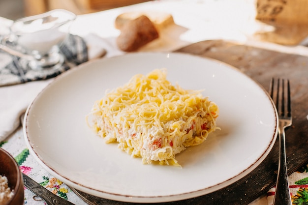 Kostenloses Foto käse mayyonaise salat gesalzen pfeffer lecker in weißen platte auf braunem holz schreibtisch