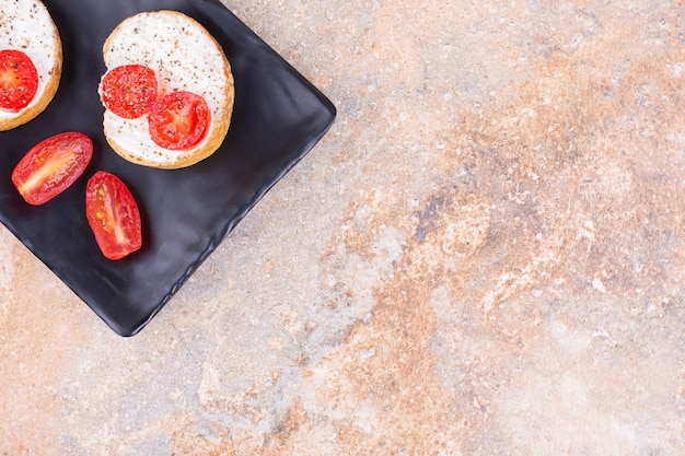 Käse mit Brot und Tomaten auf einer Platte, auf dem Marmorhintergrund.