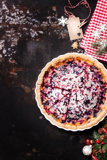 Käsekuchen mit Himbeeren auf einem dunklen Holztisch mit Weihnachtsdekoration