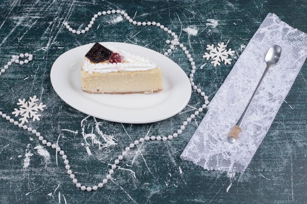 Käsekuchenscheibe auf weißem Teller mit Löffel und Perlen. Hochwertiges Foto