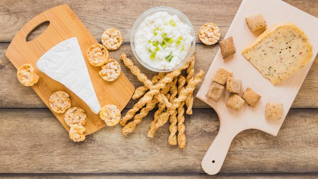 Käseplätzchen und Brotstöcke mit Käse in der Schüssel auf hölzernem Hintergrund