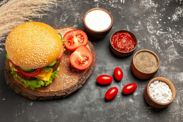 Käsiger Fleischburger der Draufsicht mit Gewürzen auf den dunklen Bodenbrötchensandwich-Fleischpommes