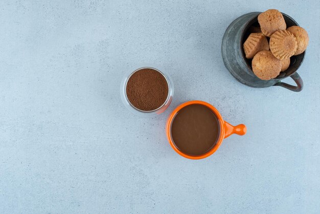 Kaffee, gemahlener Kaffee und Kuchen auf Blau