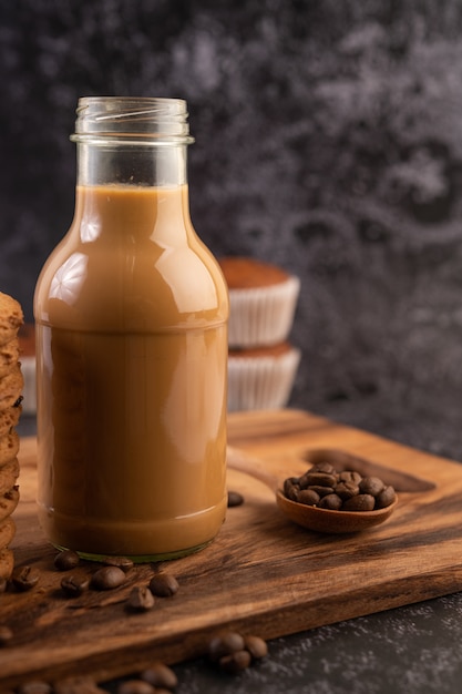 Kaffee in der Flasche mit Kaffeebohnen auf einem Holzteller.