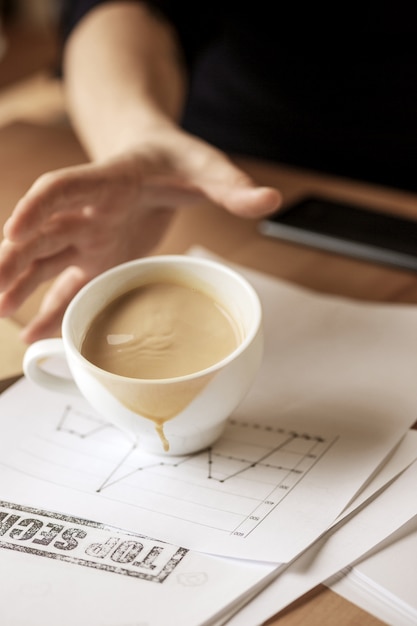 Kostenloses Foto kaffee in der weißen schale, die morgens auf dem tisch am bürotisch verschüttet wird