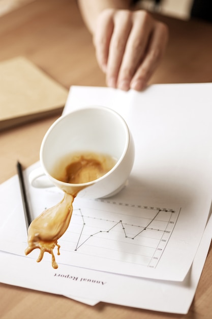 Kaffee in der weißen tasse verschüttet auf dem tisch am morgenarbeitstag am bürotisch