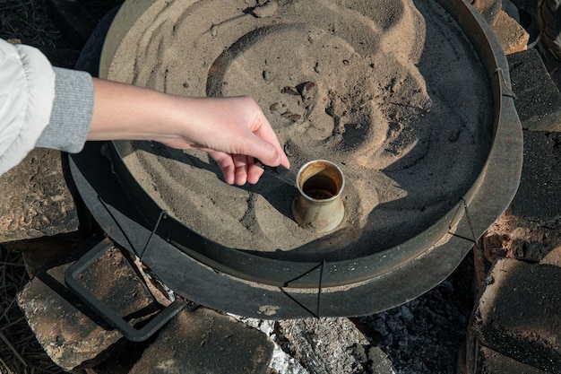 Kaffee in einem Türken auf dem Sand, der türkischen Kaffee macht.