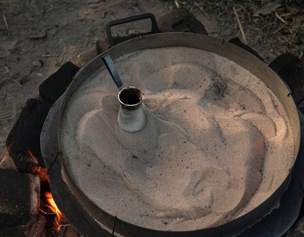 Kaffee in einem Türken auf dem Sand, der türkischen Kaffee macht.