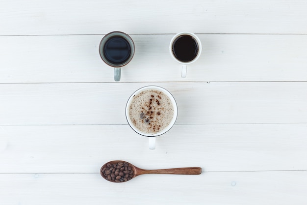 Kaffee in Tassen mit Kaffeebohnen-Draufsicht auf einem hölzernen Hintergrund
