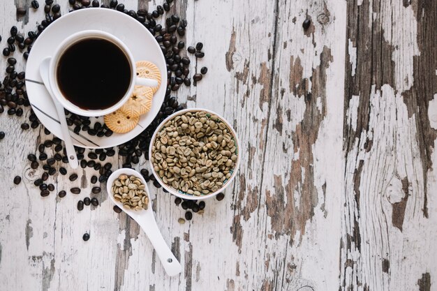 Kaffee mit Plätzchen nahe nicht gerösteten Kaffeebohnen