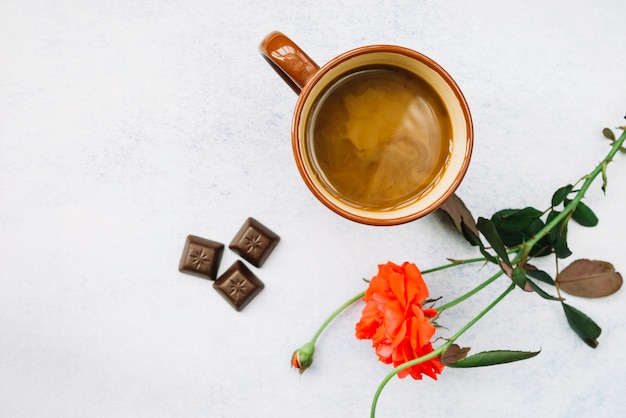 Kaffee mit schönen Rosen- und Schokoladenstücken auf weißem Hintergrund