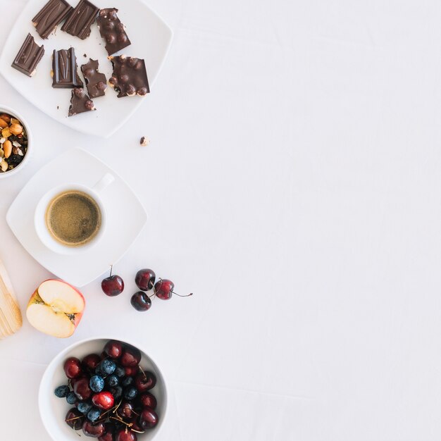 Kaffee mit Trockenfrüchten; Schokoladenstücke und Früchte auf weißem Hintergrund