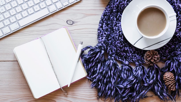 Kaffee und Notebook in der Nähe von Schal und Tastatur