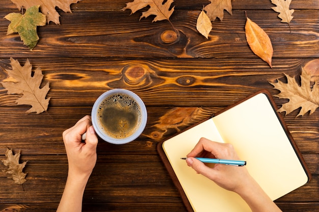 Kaffee und Notizbuch auf hölzernem Hintergrund