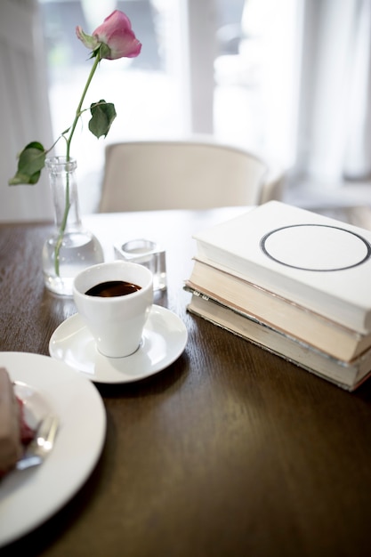 Kaffee und Rose in der Nähe von Büchern