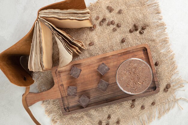 Kaffee- und Schokoladenstücke auf Holzbrett mit Bohnen und Notizbuch.