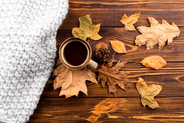 Kaffee und trockene Blätter auf hölzernem Hintergrund