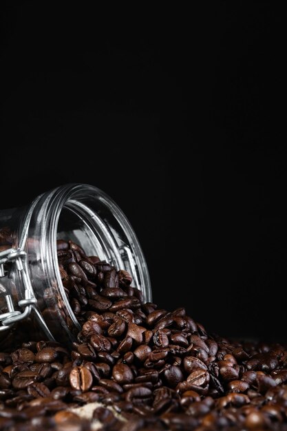 Kaffeebohnen in einem Glasgefäß auf schwarzem Hintergrund Closeup selektiven Fokus vertikalen Rahmen Rösten und Zubereiten von Kaffee vertikalen Rahmen