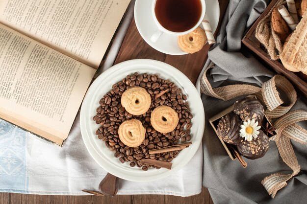 Kaffeebohnen, Kekse, Pralinen und eine Tasse Tee